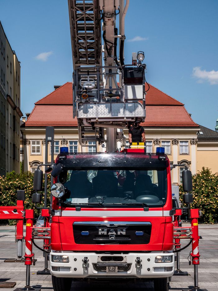 Front view of a red fire truck with an extended ladder outdoors in a city center.