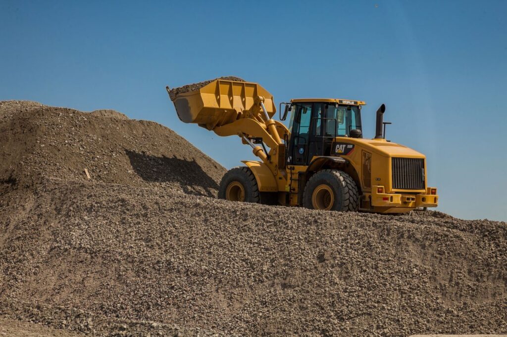 A large wheel loader moving gravel at an outdoor construction site.