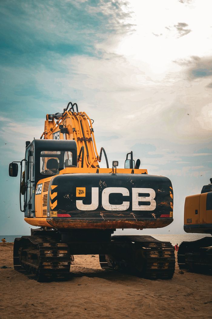 A JCB excavator on a construction site under a cloudy sky.