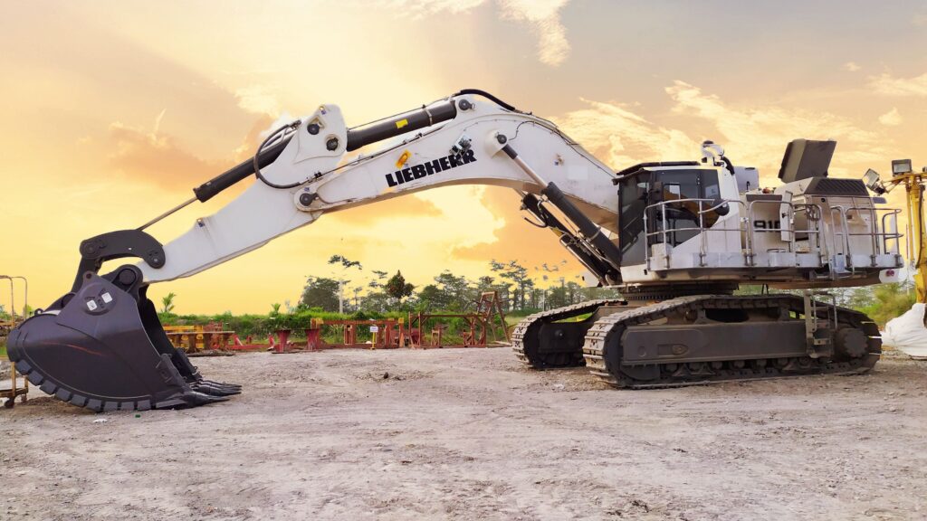 A large Liebherr excavator on a construction site in Kalimantan Selatan, Indonesia, at sunset.