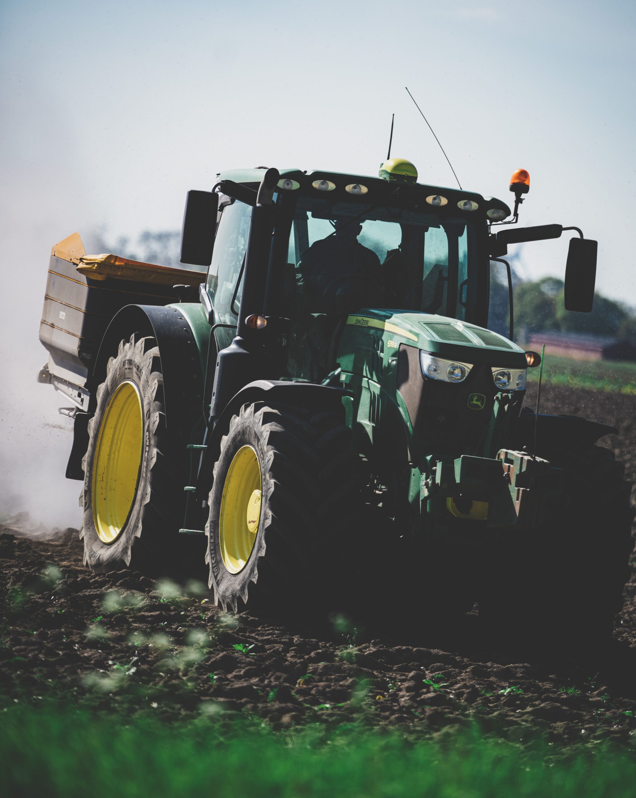 A green tractor at work plowing a field on a sunny day in Rutten, Netherlands.
