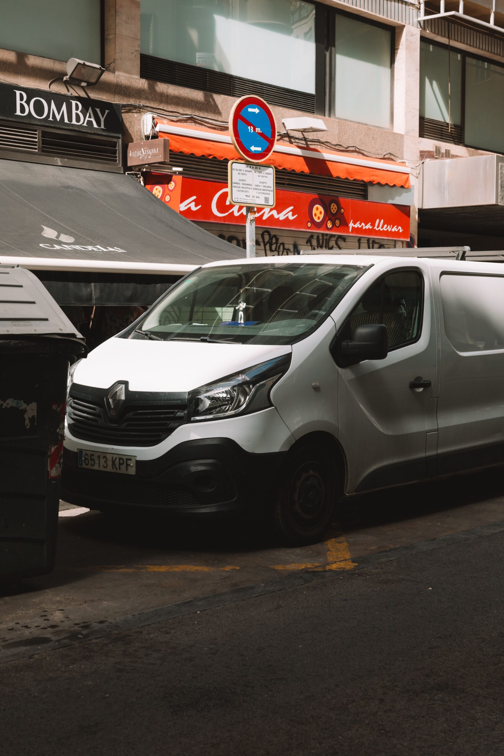 White Renault van parked on a busy city street with urban building backdrop.