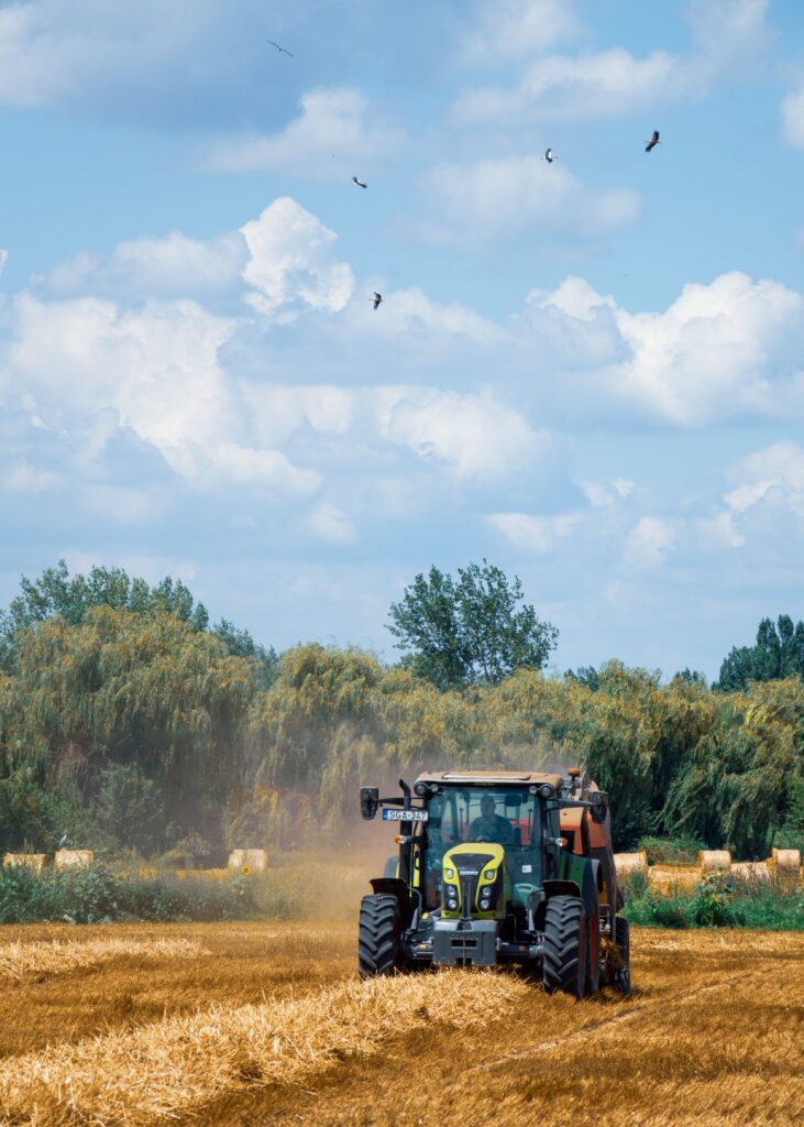 A vibrant farm scene shows a tractor working in a golden field under a bright sky.
