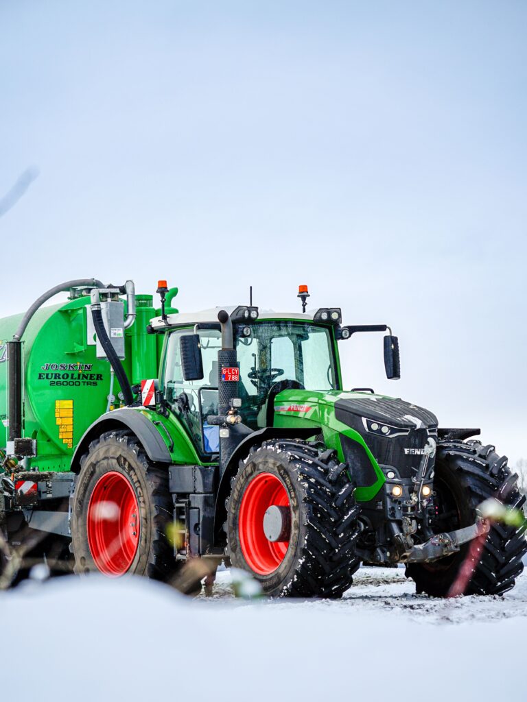 A green tractor working on a snowy field in Retie, Flanders, Belgium.
