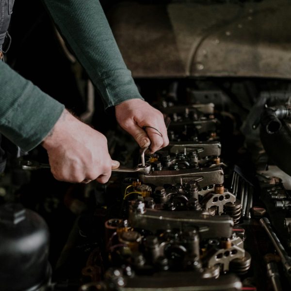 Close-up of a mechanic's hands using tools to repair an engine. Indoor setting.
